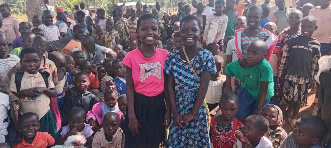 Zwei Mädchen vor vielen Kindern unseres Centers in Uganda