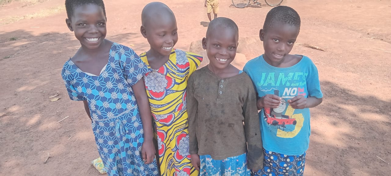 Vier lächelnde Kinder in Uganda, für die wir Mais anbauen und ernten