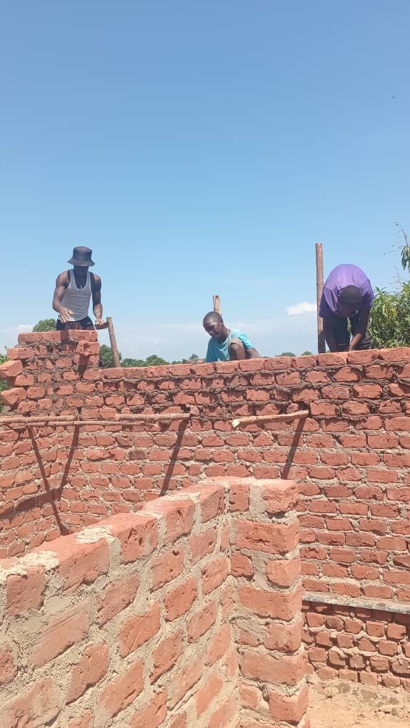 Drei Männer arbeiten oben auf der fast fertigen Mauer