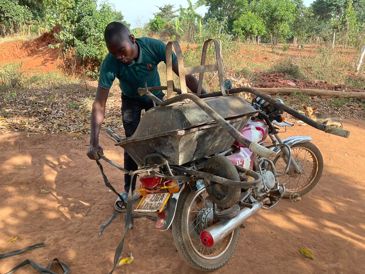 A young man loading a wheelbarrow onto a motorbike